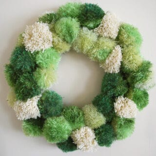 Yarn Pom Poms in wreath shape in green shades and white color.