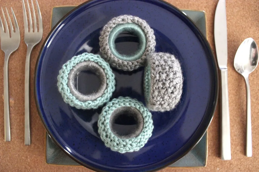 Four knitted napkin rings in seed stitch on a blue dinner plate