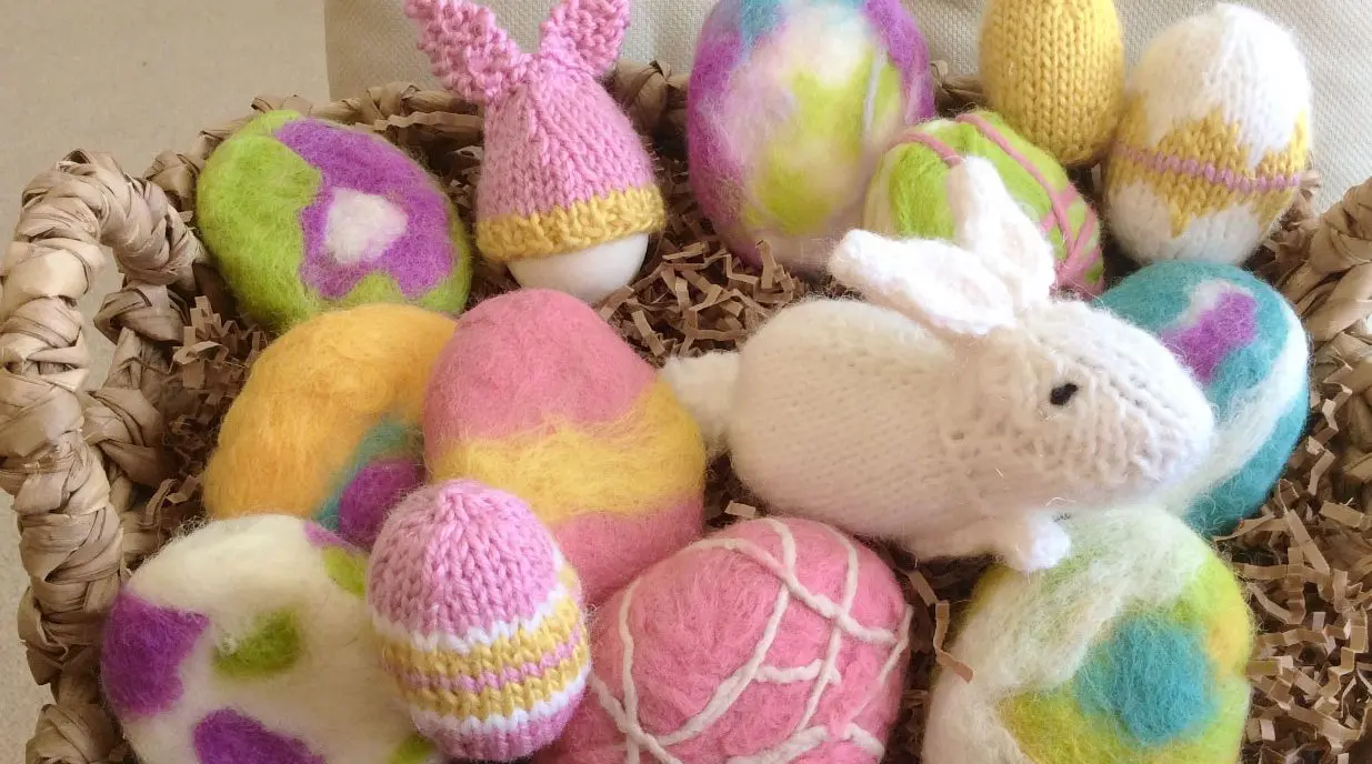 A group of felted soap and stuffed knitted bunny and easter eggs in a basket