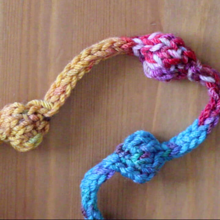 Knitted necklace with beaded texture in yellow, pink, and blue color yarn.