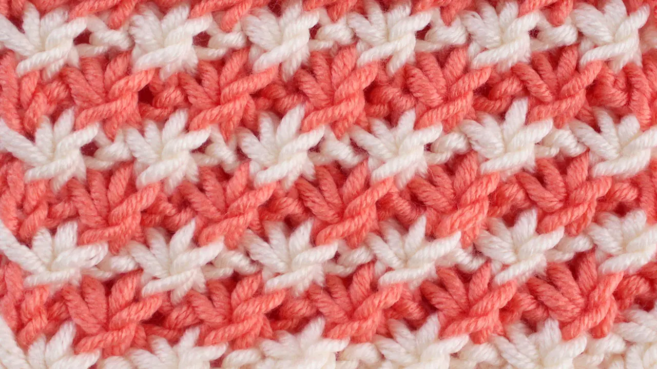 Close up a swatch of Daisy Stitch in orange and white yarn