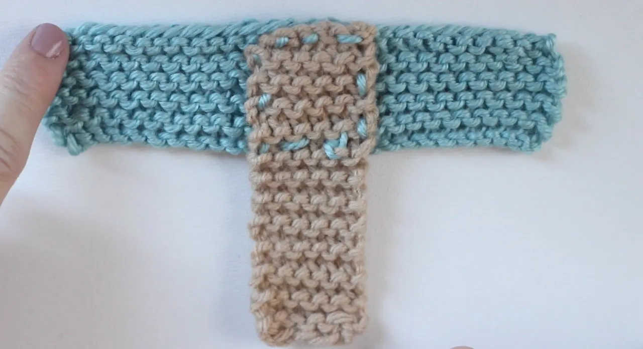 Two knitted swatches connected with yarn to create baby booties