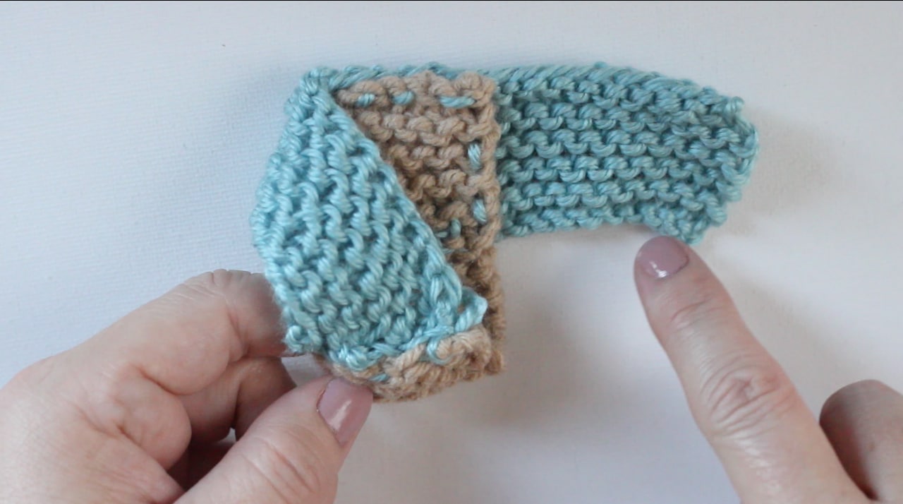 Constructing knitted baby booties by tacking the second swatch to the toe of the first