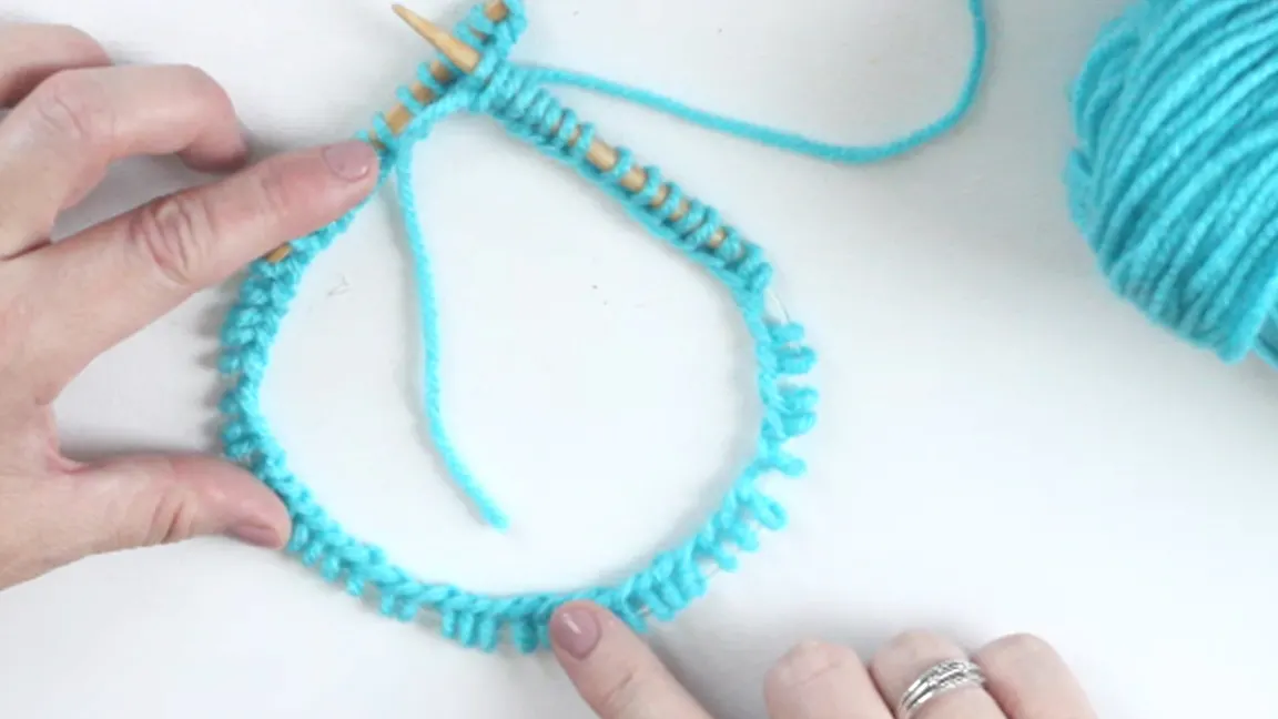 Hands demonstrating how to make sure you are not twisting your stitches when casting onto a circular needle.