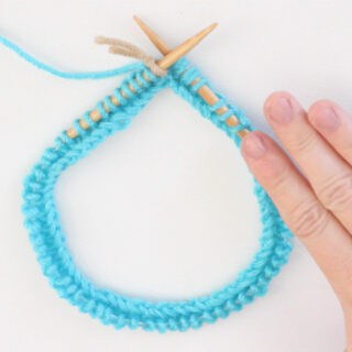 Circular Knitting Needle with blue color yarn cast on and woman's hand