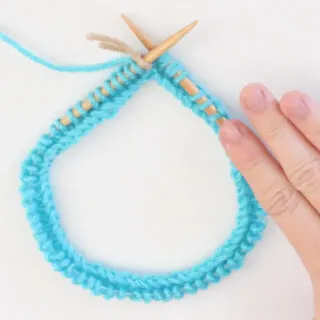 Circular Knitting Needle with blue color yarn cast on and woman's hand