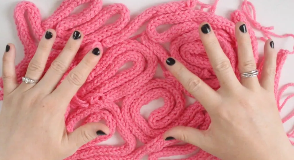 Hands and knitted icords in pink yarn
