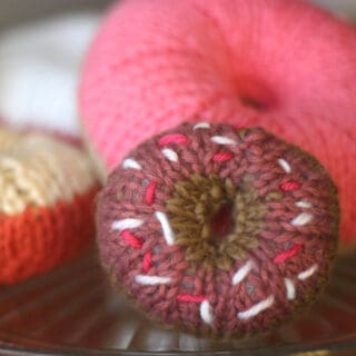 Knitted donut with sprinkle designs in yarn.
