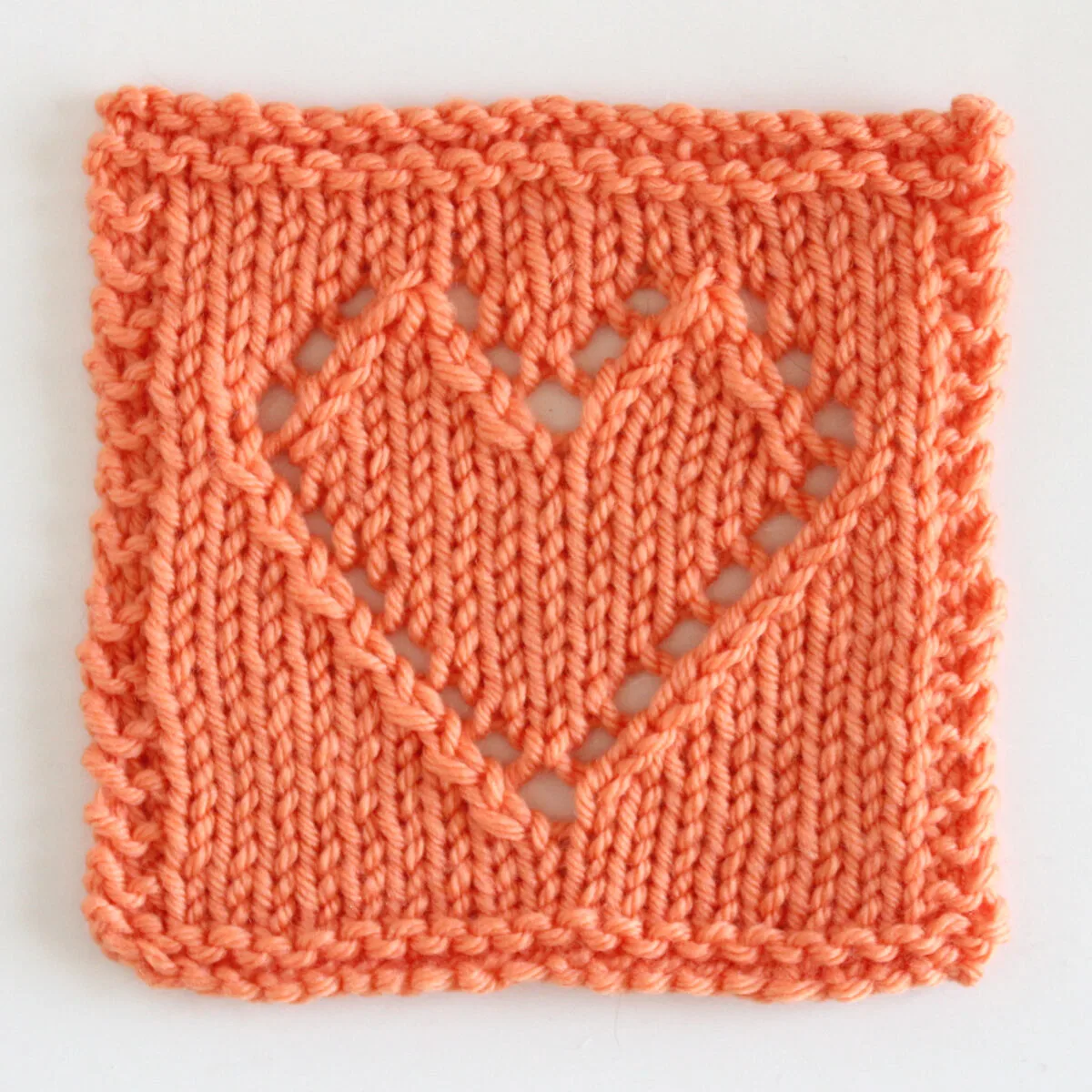 Knitted heart square in lace eyelets with orange color yarn.