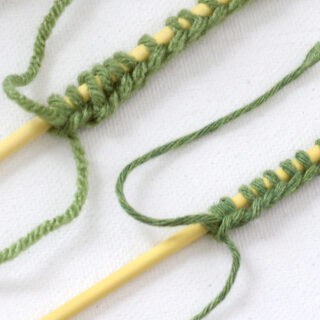 Two knitting needles with green color yarn cast on.
