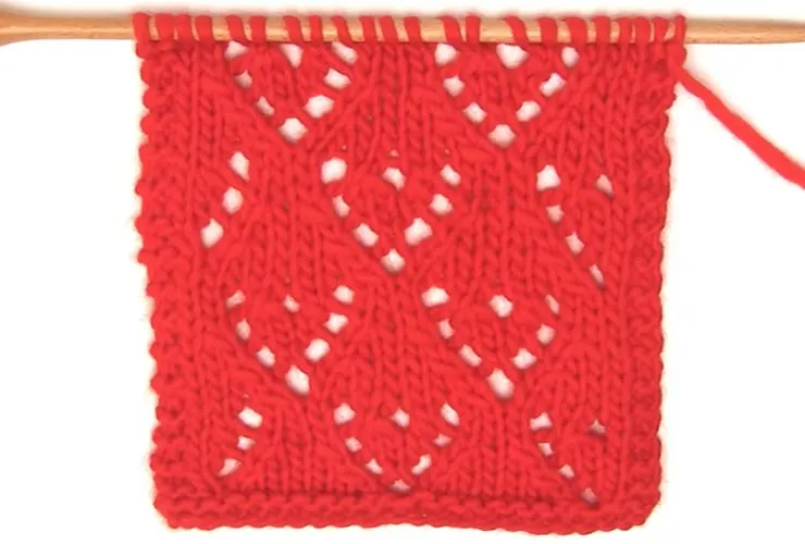 Mini Lace Heart Stitch Knitting Pattern in red colored yarn on a knitting needle.