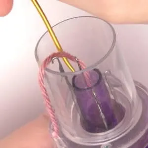 A tapestry needle moving yarn inside the Embellish Knit device.