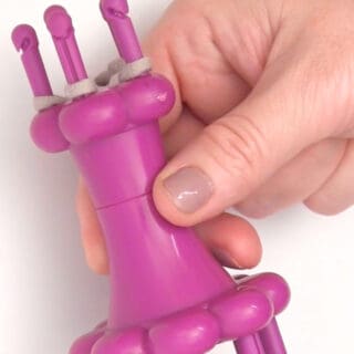 Spool Loom Knitting tool held by woman's hand.