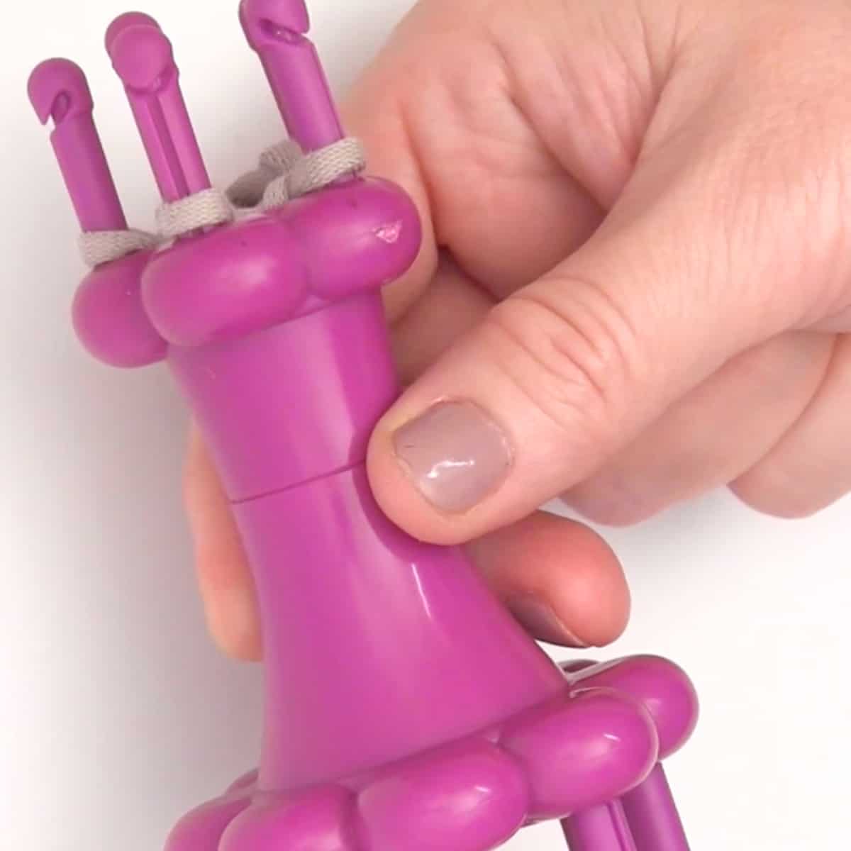 Spool Loom Knitting tool held by woman's hand.