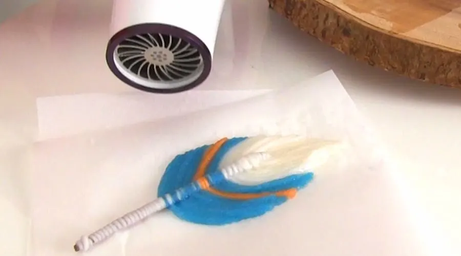 Drying a crafted fiber feather with a hair dryer.