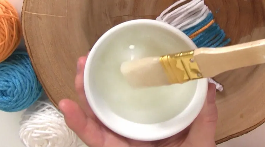 A close up of a bowl and paint brush with paste.