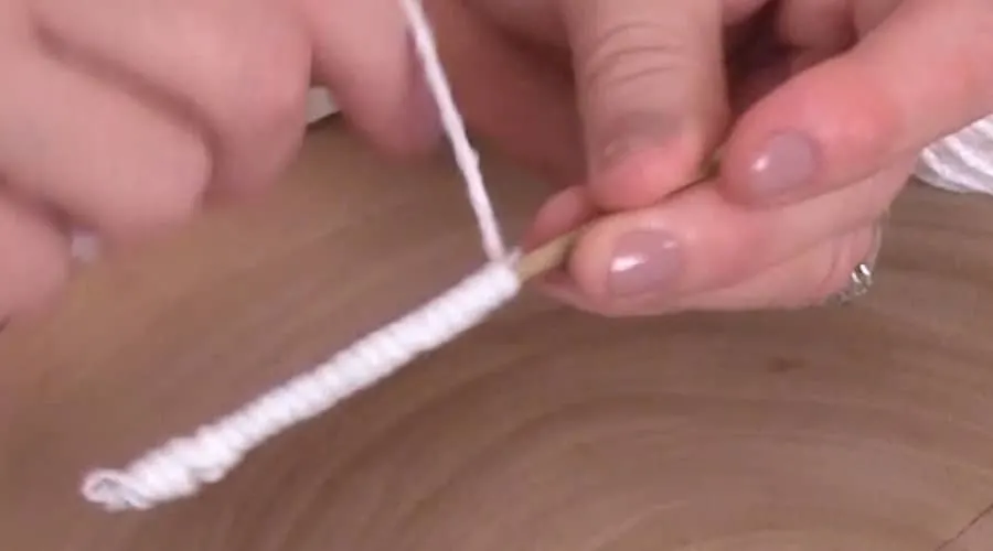 Hands wrapping yarn around craft wire.