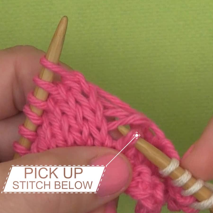 Picking up the dropped stitch with a knitting needle.
