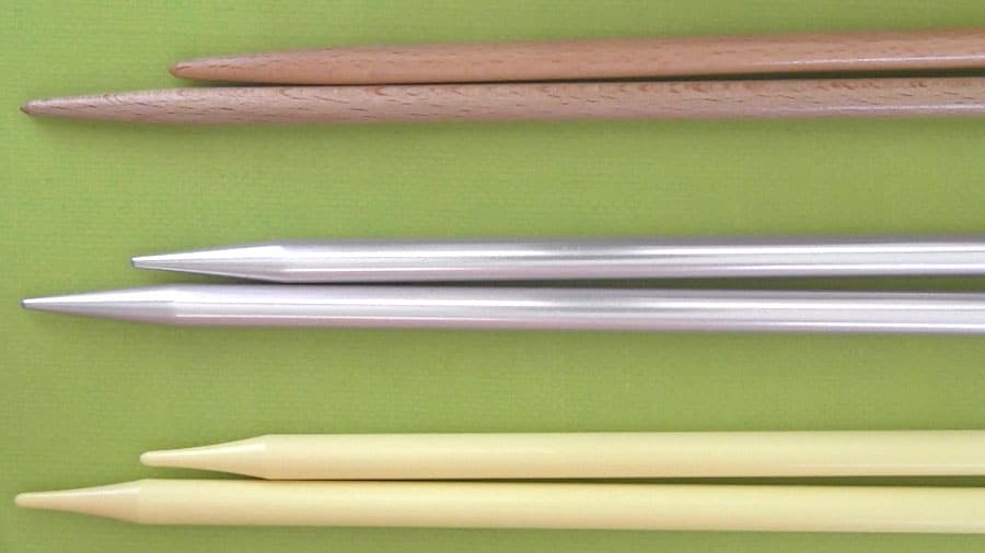 Close up of pairs of knitting needles in wood bamboo, metal, and plastic materials