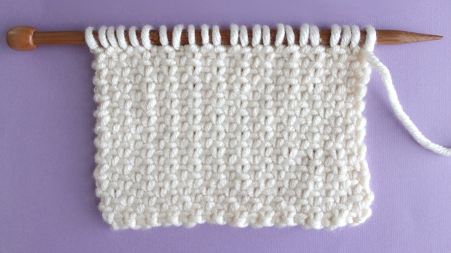 Right side of the Linen Stitch in white color yarn on bamboo knitting needle.