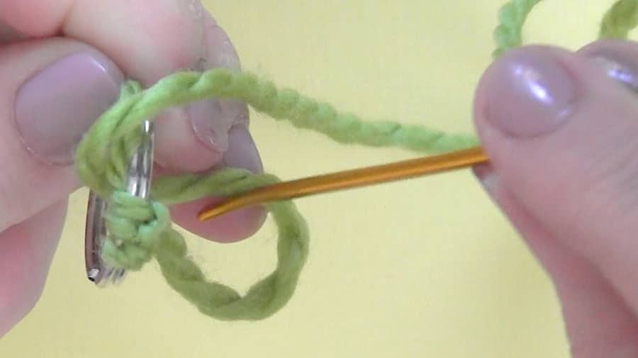 Winding green yarn around a tapestry needle.
