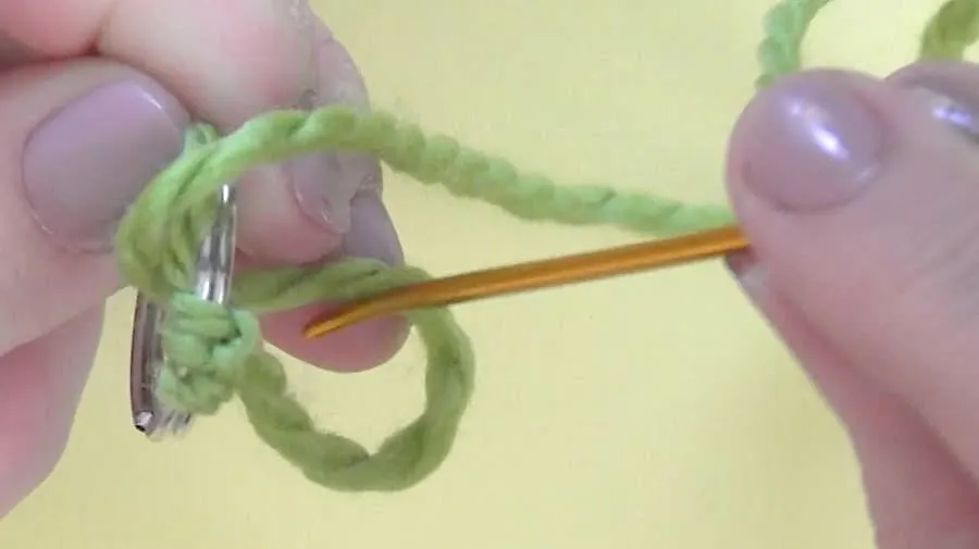 Winding green yarn around a tapestry needle.