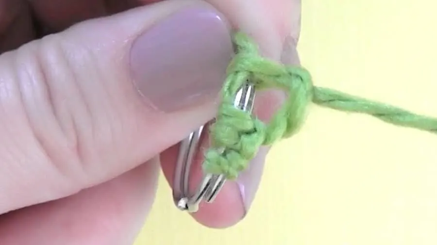 Adding green yarn to a key ring.