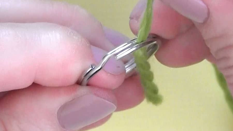 Adding green yarn to a key ring.