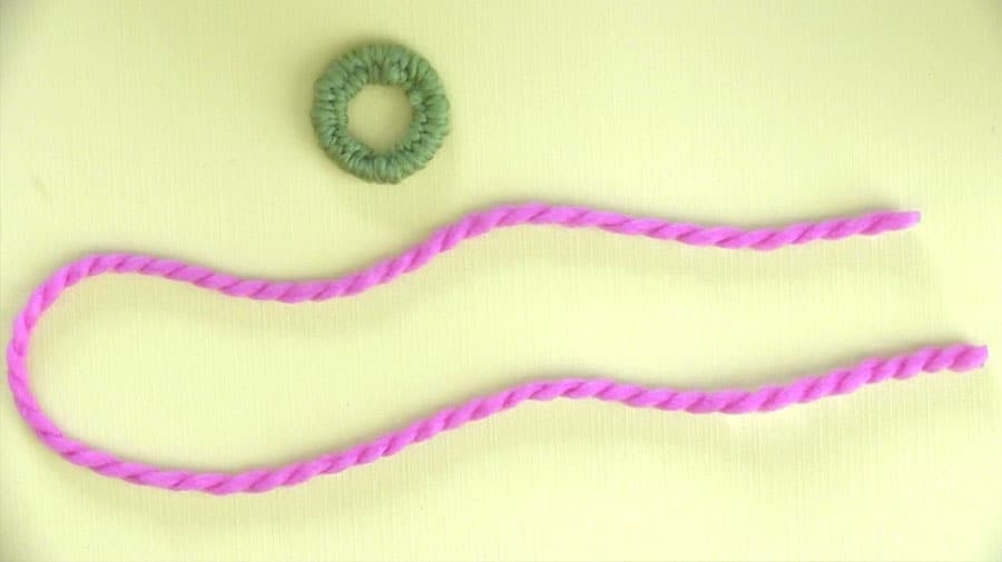 A dorset button with strands of yarn.