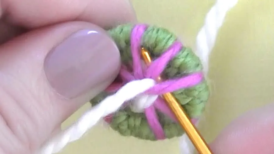 Using a tapestry needle to weave yarn around the key ring.