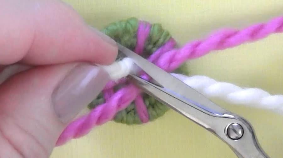A small pair of scissors cutting yarn from the dorset button.