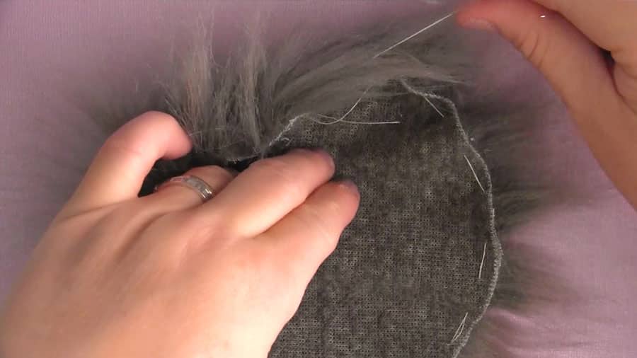 A close up of a hand cinching up the sewn edges of faux fur.