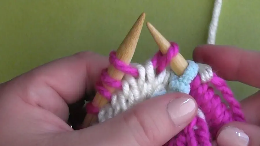 Knitting demonstration with pink yarn and needles.