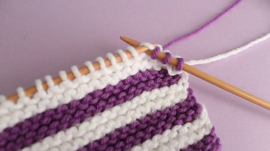 Changing from white to purple yarn on knitting needles.
