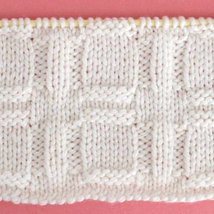 Close up a swatch of textured Window Stich in white yarn on a knitting needle