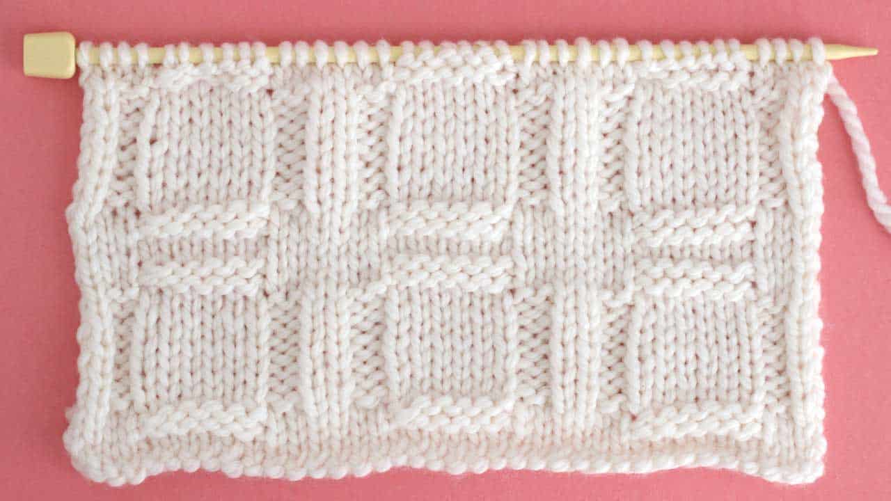 Close up a swatch of textured Window Stich in white yarn on a knitting needle