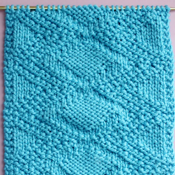 Knitted Swatch of the Fancy Diamond Knit Stitch Pattern texture in blue color yarn on a straight knitting needle.