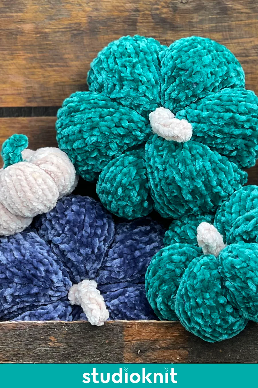 Velvet knitted pumpkins stacked atop each other in blue, green, and white yarn colors