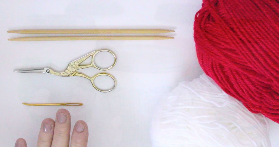 Knitting Needles, Scissors, a Tapestry Needle, with red and white yarn to make a Mini Stocking