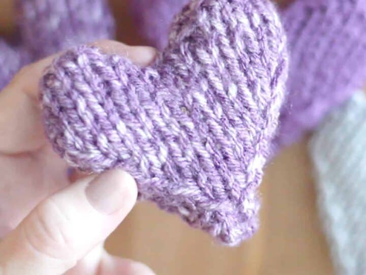 puffy stuffed knitted heart with hand holding