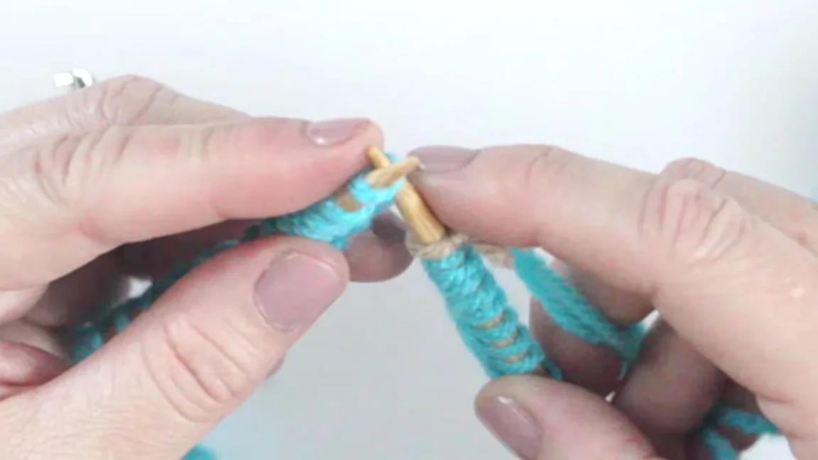 Hands demonstrating how to join yarn on circular knitting needles with blue color yarn.