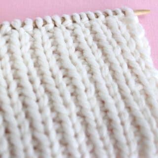 1x1 Rib Knit Stitch Pattern in white color yarn on knitting needle.