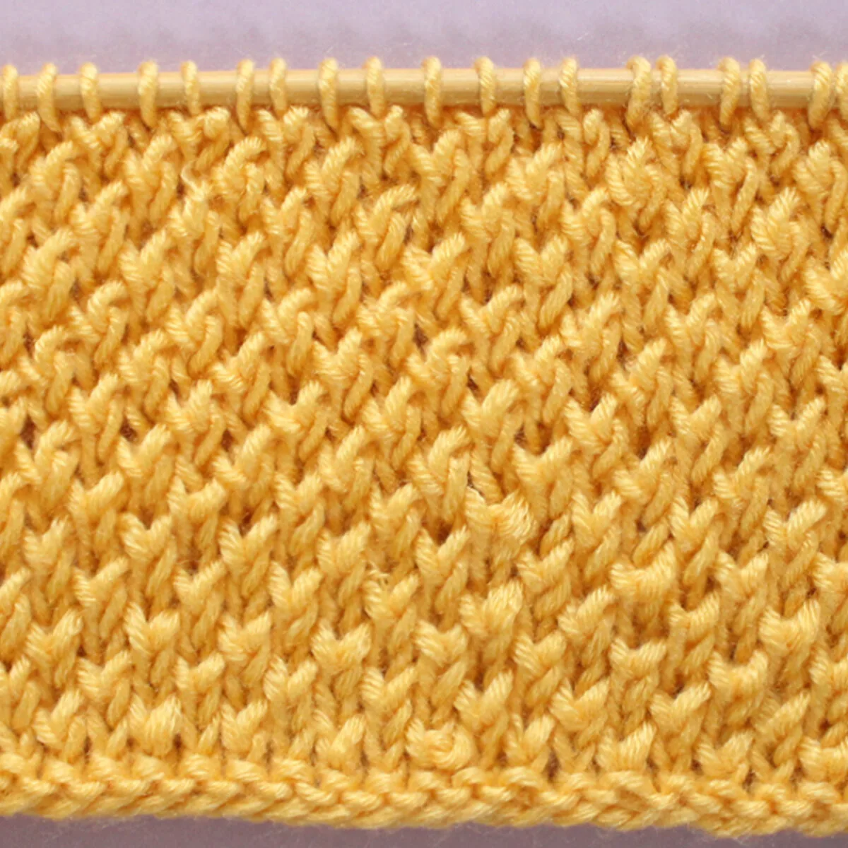 Bee Stitch Knitting Pattern texture in yellow color yarn on knitting needle.