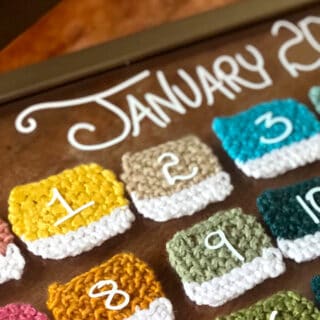 Knitted swatches inside a glass frame to create a calendar with numbers on each.