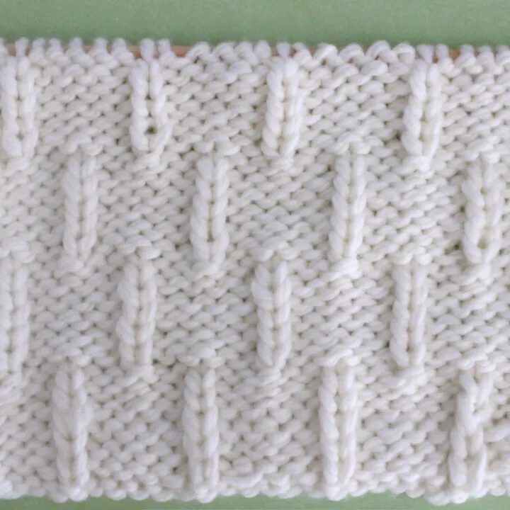 Caterpillar Knit Stitch Pattern in white yarn on knitting needle.