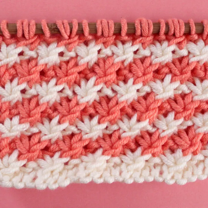 Daisy Stitch Knitting Pattern texture in alternating orange and white colors of yarn on knitting needle.