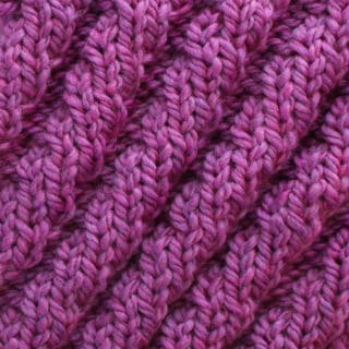 Knitted Diagonal Spiral Rib Stitch Pattern texture in purple color yarn.