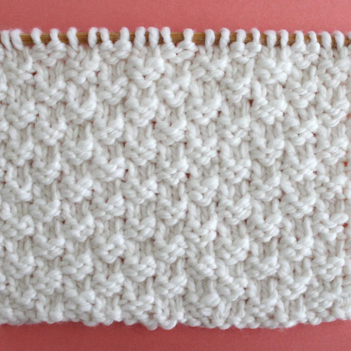 Double Moss Knit Stitch Pattern in white yarn on knitting needle.