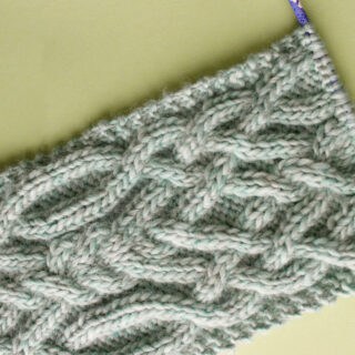Knitted Fancy Celtic Cable Stitch Scarf in Green yarn color on a knitting needle.