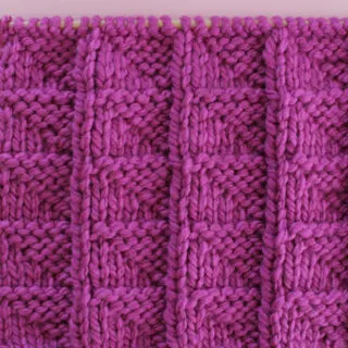 Knitted Flag Stitch Pattern in purple yarn on knitting needle.